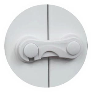 Białe zabezpieczenie szafek t.b.t. przymocowane do białych drzwi szafek.