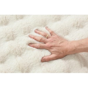 Dłoń na miękkim, beżowym dywanie shaggy. Puszysty dywan t.b.t.