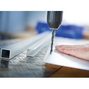 Wiertło do metalu LUX wierci w metalowej płycie, średnica 6,5 mm.