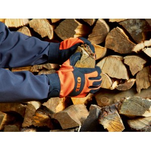 Dłonie w rękawicach roboczych OBI (rozmiar 10) trzymają drewno przed stosem drewna. Odzież ogrodowa.