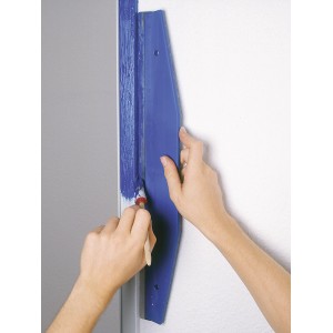 Liniał do przycinania LUX 60 cm w użyciu podczas malowania ściany niebieską farbą.