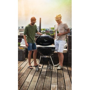 Akcesoria do grilla: Dwóch mężczyzn grilluje na grillu kulistym na tarasie na dachu.