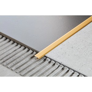 Złoty profil do płytek między dwiema płytkami.