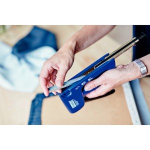 Osoba ładuje niebieski zszywacz zszywkami z cienkiego drutu.