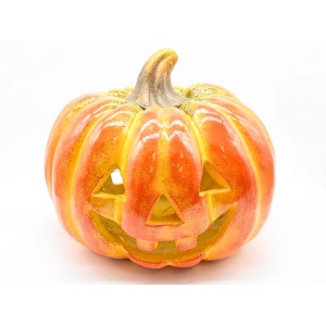 Pomarańczowa dynia jako dekoracja ogrodowa na Halloween z rzeźbioną twarzą.