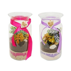 Dwie dekoracyjne szklane butelki "Las w szkle" z roślinami, piaskiem i wstążką.