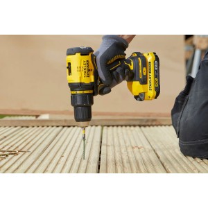 Żółta wiertarko-wkrętarka akumulatorowa Stanley Fatmax wkręca w drewno.