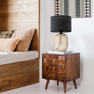 Dekoracyjna lampa stołowa z czarnym abażurem na drewnianym stoliku nocnym.