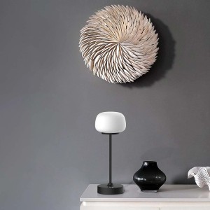 Dekoracyjna lampa stołowa t.b.t. z białym kloszem i czarną podstawą.