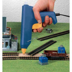 Niebieski pistolet do kleju na gorąco klejący tory kolejki modelarskiej.