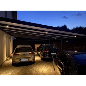 Nowoczesna wiata garażowa z trzema zaparkowanymi samochodami w nocy.