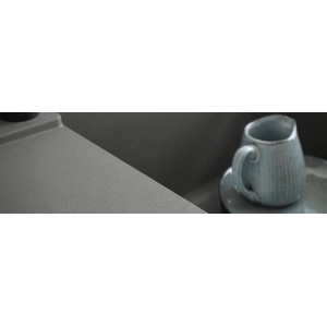 Zbliżenie szarego zlewozmywaka granitowego t.b.t. z kubkiem.