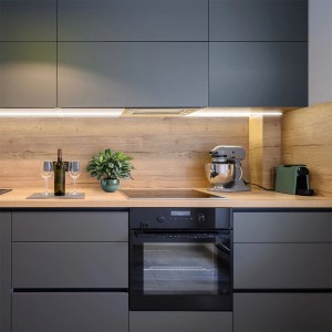 Nowoczesna kuchnia z szarymi szafkami i oświetleniem LED pod szafkami wiszącymi.