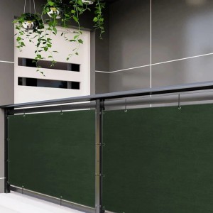 Ciemnozielona mata na ogrodzenie t.b.t. zamocowana na balustradzie balkonu.