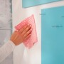 Ręka wyciera białą ścianę czerwoną ściereczką. Aplikacja taśmy klejącej.