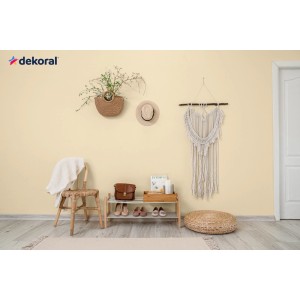 Pokój dzienny z farbą do ścian w odcieniu żółtym. Elementy dekoracyjne, takie jak dekoracje ścienne i półki.