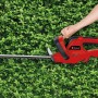 Elektryczne nożyce do żywopłotu Einhell GH-EH 4245 w użyciu na tle zielonego żywopłotu.