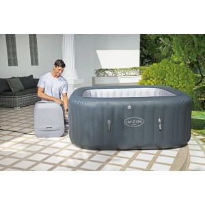 Nadmuchiwana szara wanna z hydromasażem z mężczyzną i pompą w ogrodzie.
