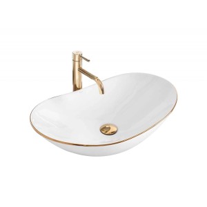 Owalna umywalka nablatowa t.b.t. w kolorze białym ze złotymi akcentami i baterią.