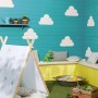 Kącik zabaw dla dzieci z tipi, piaskownicą i pomalowaną na niebiesko drewnianą ścianą z motywami chmur.