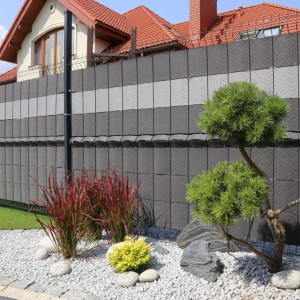 Szara mata na ogrodzenie t.b.t. z dekoracją w ogrodzie.