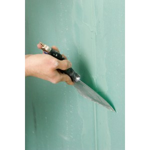 Ręka nakłada szpachlę Knauf Uniflott na zieloną ścianę z płyt gipsowo-kartonowych. Akcesoria do suchej zabudowy.