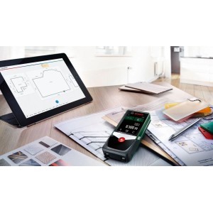 Miernik laserowy Bosch PLR 50 C na stole z tabletem i planami.