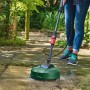 Osoba czyści taras myjką ciśnieniową Bosch Universal Aquatak 125 i zielonym środkiem do czyszczenia powierzchni. Czyste płyty.