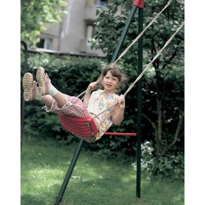Dziewczynka huśta się na czerwonej huśtawce dla dzieci w ogrodzie.
