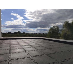 Ułożone szare płytki placu zabaw t.b.t. z połączeniem puzzli na tarasie na dachu.