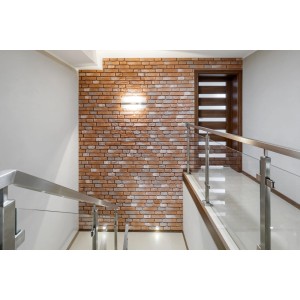 Aranżacja ściany z czerwonymi płytkami ceglanymi t.b.t. na klatce schodowej.