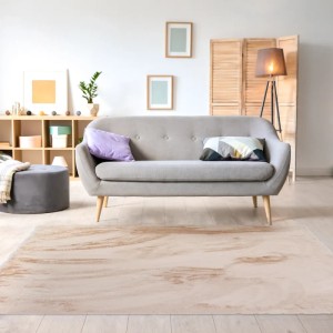 Beżowy dywan z długim włosiem w salonie przed szarą sofą.